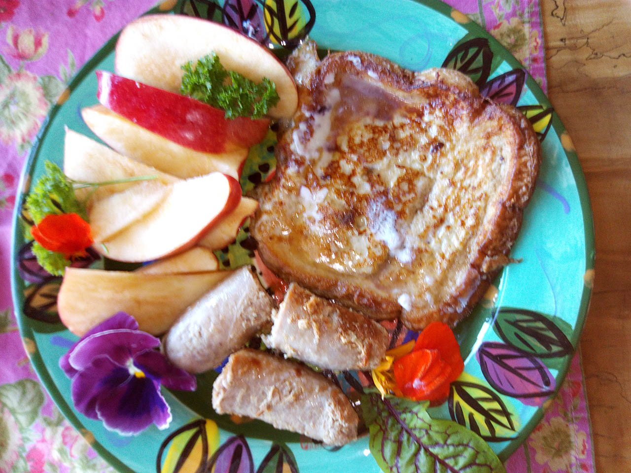 Plate of French toast, apples, sausage.