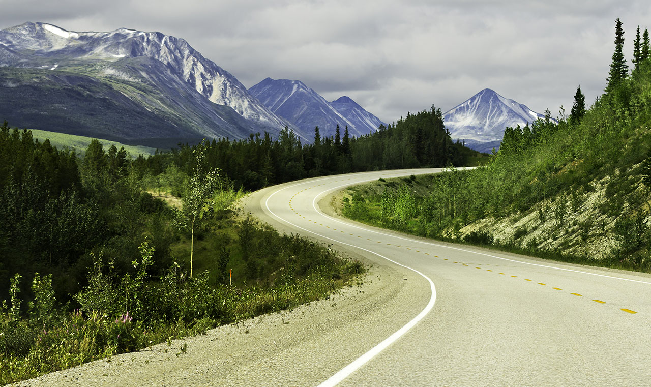 Curved asphalt road in high mountains of Alaska
