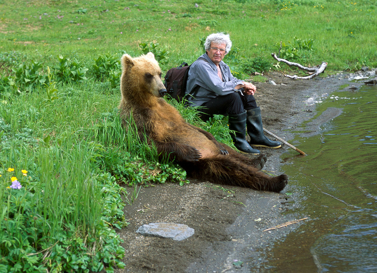 Person sitting with a brown bear.